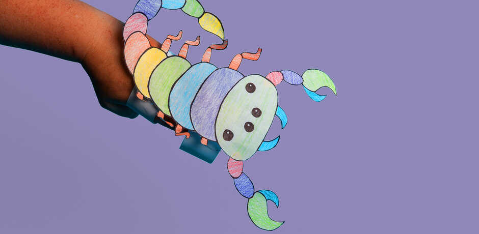 A colorful paper scorpion craft against a lavender background