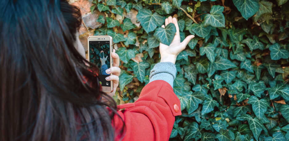 A woman uses the iNaturalist app to identify a plant