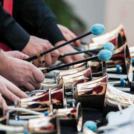 Close-up of musicians playing brass bells with mallets 