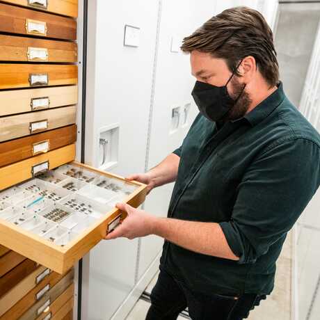 Image of Christopher Grinter with a specimen drawer.