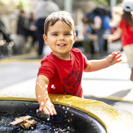Young boy happily splashes at Riveropolis station at Academy's Spring in the Garden festival